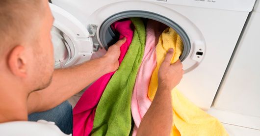 Persona metiendo ropa a lavadora